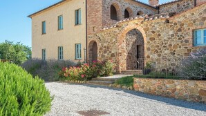 A two-story stone building with a gravel driveway and a small garden with pink flowers. - Apartment Cipresso-Cignella Resort in Tuscany (Siena)