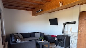 Un salon moderne avec un plafond en bois, un canapé d’angle gris, une petite table basse et une cheminée.