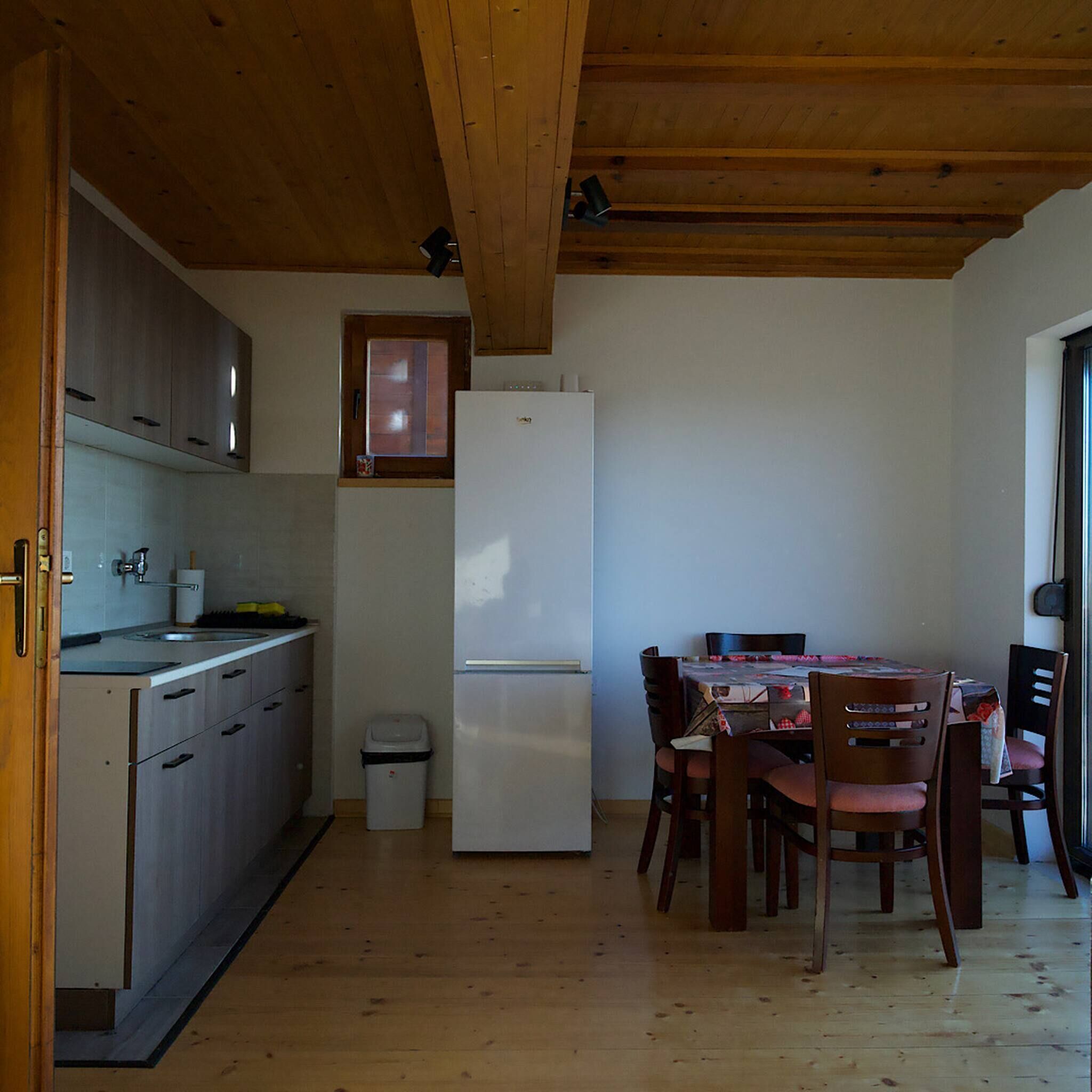 A compact kitchen with wooden cabinets, a white refrigerator, a sink, and a dining area with a table and chairs.