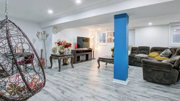 A modern living room with a hanging chair, a sofa, a TV, and decorative items. - A very peaceful home (Oshawa)