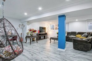 A modern living room with a hanging chair, a sofa, a TV, and decorative items.