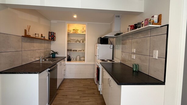 Une cuisine moderne avec des meubles blancs, un îlot central et un four encastré.