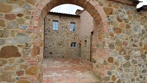 Un bâtiment en pierre doté d’une cour intérieure, avec un chemin en briques et un petit escalier menant à un niveau supérieur.