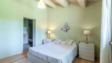 Une chambre à coucher avec un lit, deux tables de chevet avec des lampes, une décoration murale représentant des papillons et un plancher en bois.