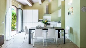 Una cocina moderna con armarios blancos, una mesa de comedor con sillas y vistas a zonas verdes.