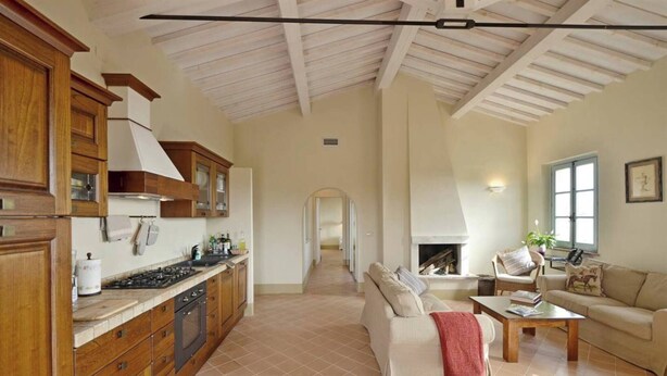 A spacious living area with a fireplace, wooden cabinets, and a tiled floor. - Quercia Apartment - Cignella Resort Tuscany (Trequanda)