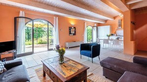 A spacious living room with a wooden ceiling, a television, a sofa, a coffee table, and a view through large glass doors to an outdoor area. - Villa Pesca amazing House in the heart of Tuscany (Tuscany City)
