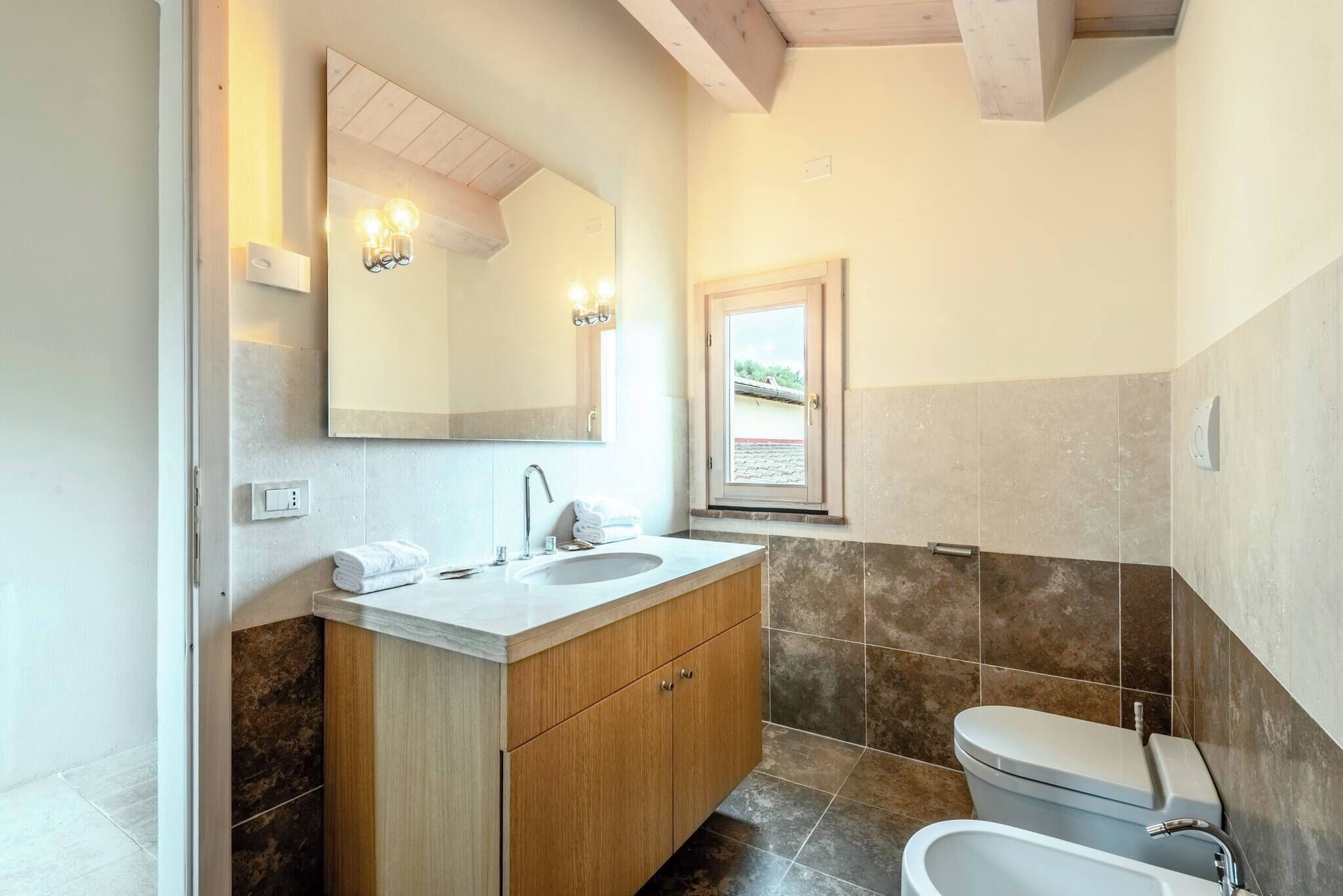 Une salle de bain moderne avec un meuble-lavabo en bois, un grand miroir et des toilettes.