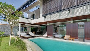 A modern house with a swimming pool, outdoor seating, and a stone wall. - Villa Pasisi 11 - Canggu (Canggu)
