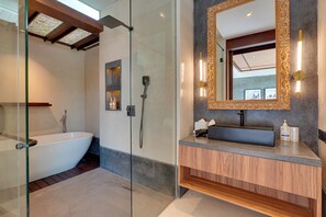 A modern bathroom with a freestanding bathtub, a glass-enclosed shower, and a vanity with a large mirror and wall sconces. - Villa Pasisi 11 - Canggu (Canggu)