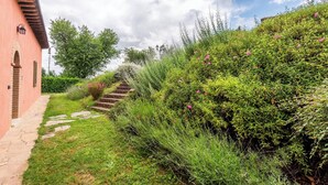 Un chemin de pierre mène à un bâtiment rose doté d’un escalier.