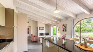 Une cuisine moderne dotée d’un grand îlot central, d’un coin repas offrant une vue agréable et d’un salon avec cheminée.