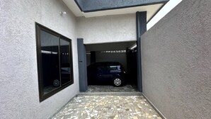 A narrow, tiled entrance with a car parked inside, a large window on the left, and a textured wall. - Mariagletta Cozy Villa (Abomey Calavi)
