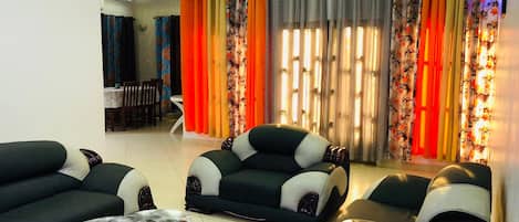 A living room with a sofa set, a coffee table, and curtains with a floral pattern.