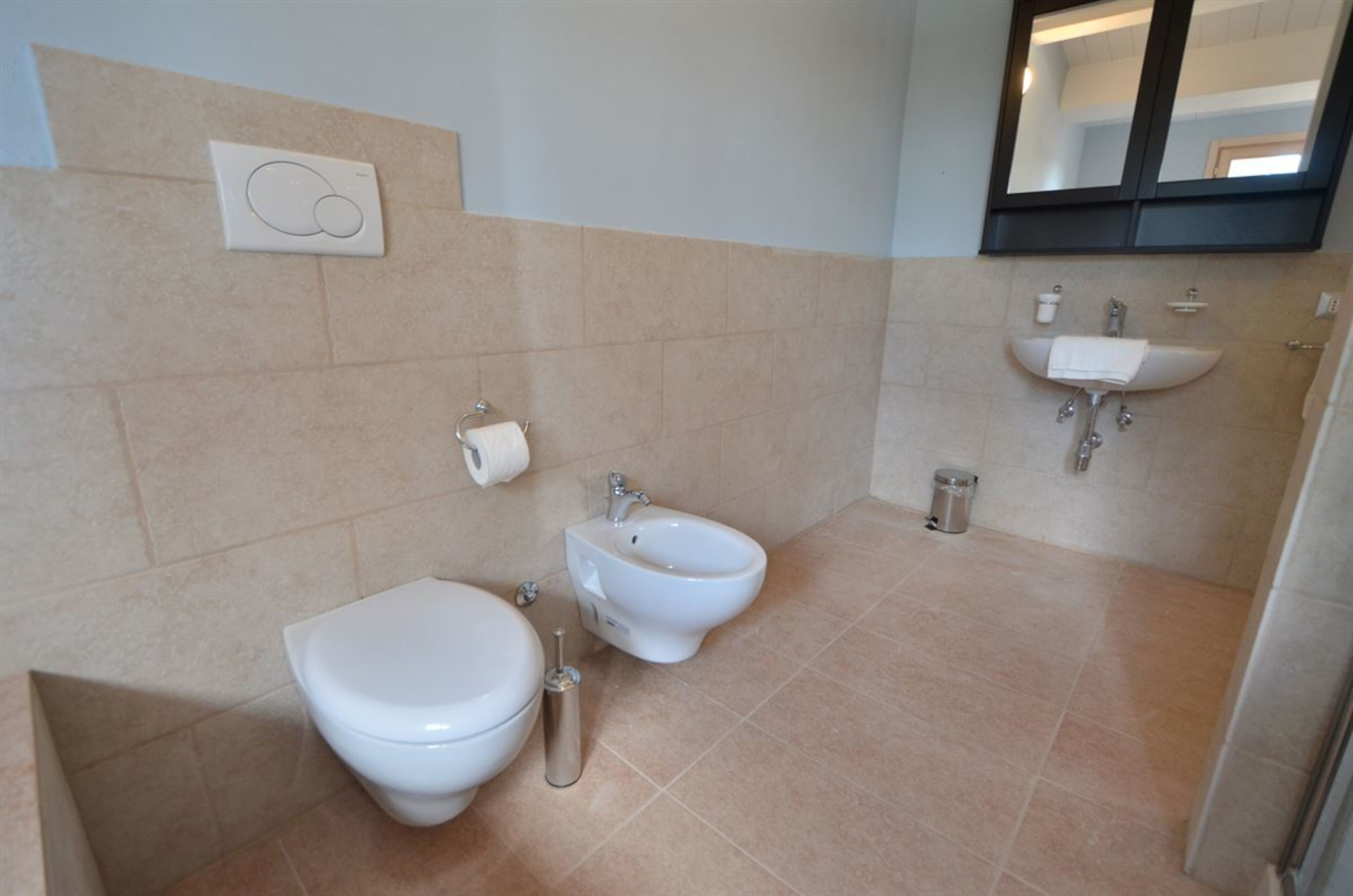 Un baño con inodoro, bidé y lavamanos.