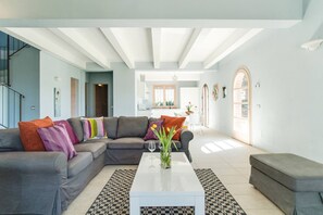 Ein modernes Wohnzimmer mit einem grauen Sofa, einem weißen Couchtisch und einem gemusterten Teppich.