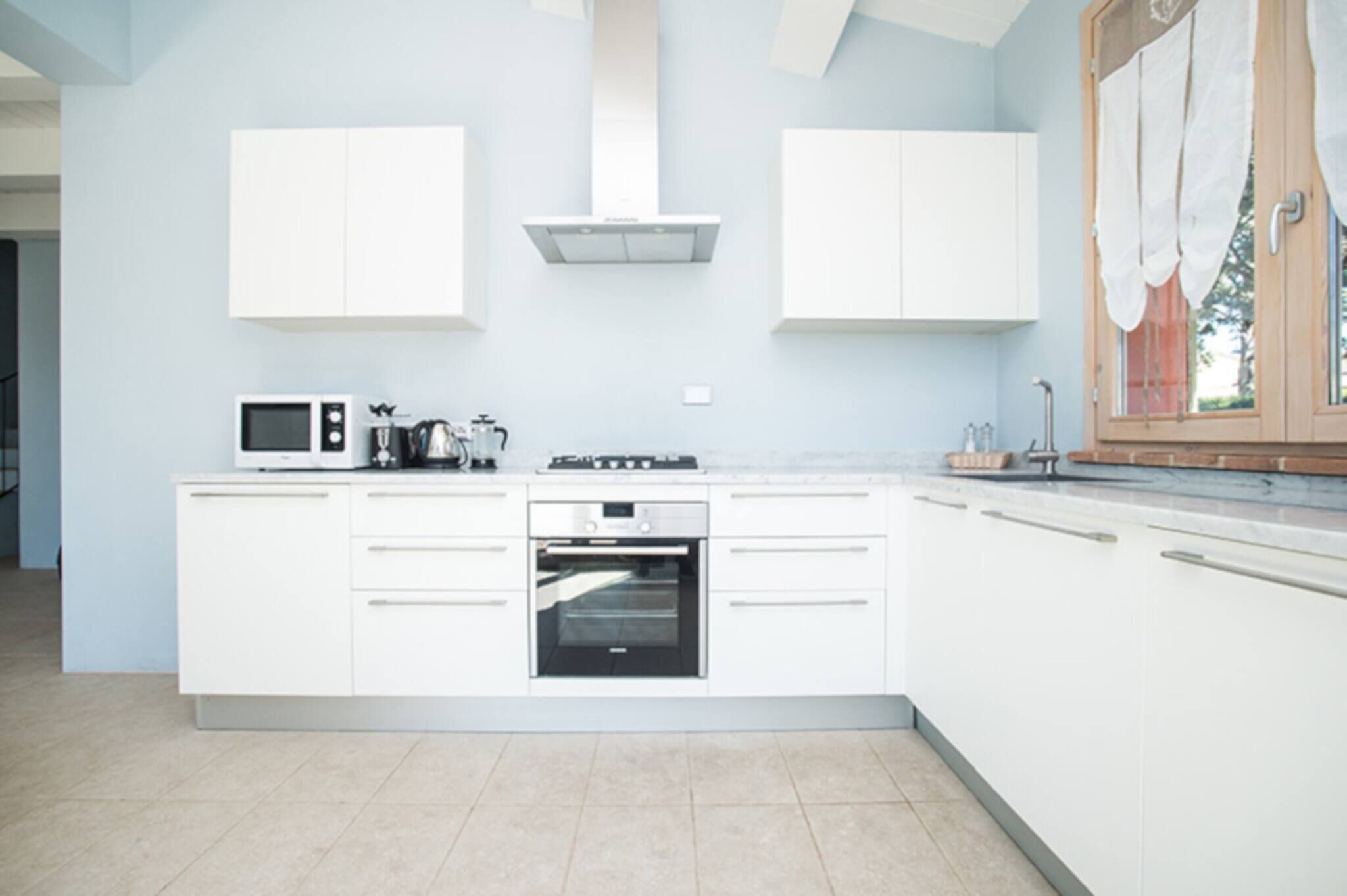 Una cocina moderna con armarios blancos, horno integrado y microondas.