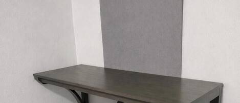 Una mesa pequeña y oscura con una sola silla.