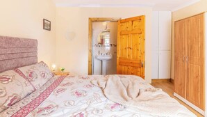 Een slaapkamer met een bed, een houten kledingkast en een badkamer die door een open deur zichtbaar is.