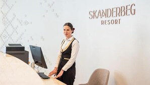 Un comptoir d’accueil à l’hôtel Skanderbeg, équipé d’un ordinateur, d’une imprimante et d’une chaise.