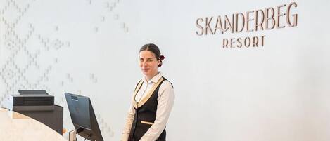 A reception desk at Skanderbeg Resort with a computer, a printer, and a chair.