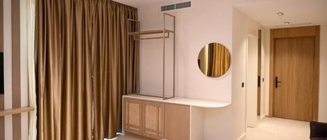 Un dormitorio moderno con cama, escritorio, espejo y armario.