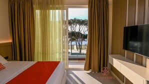 Une chambre d’hôtel avec un lit, une télévision et un balcon avec des rideaux.