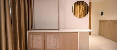 A modern room with a built-in wardrobe, a round mirror, and a wooden headboard.
