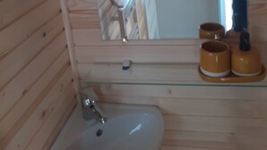 A wooden cabin bathroom with a round window, a sink, and two yellow cups on the counter. - Charming Holiday Home in Journiac with Pool Access (Journiac)