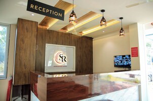 Un área de recepción con un revestimiento de panel de madera, un mostrador de recepción y un televisor montado en la pared.