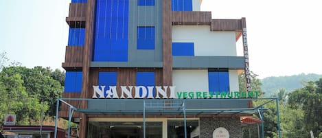 A multi-story building with signage for 'NANDINI VEG RESTAURANT' and 'SUDEV RESIDENCY BOARDING & LOPGING'.