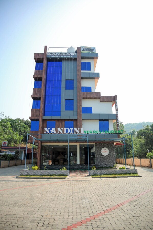 A multi-story building with signage for 'NANDINI VEG RESTAURANT' and 'SUDEV RESIDENCY BOARDING & LOPGING'. - Sudev Residency (Mangaluru)