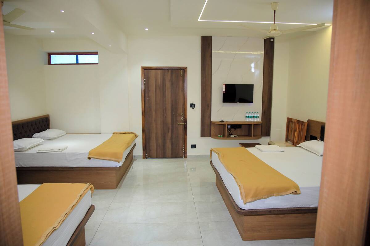 A hotel room with two beds, a TV, and a wooden wardrobe.