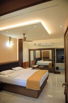 Habitación de hotel con una cama grande, ventilador de techo, unidad de aire acondicionado y un espejo que refleja la habitación.