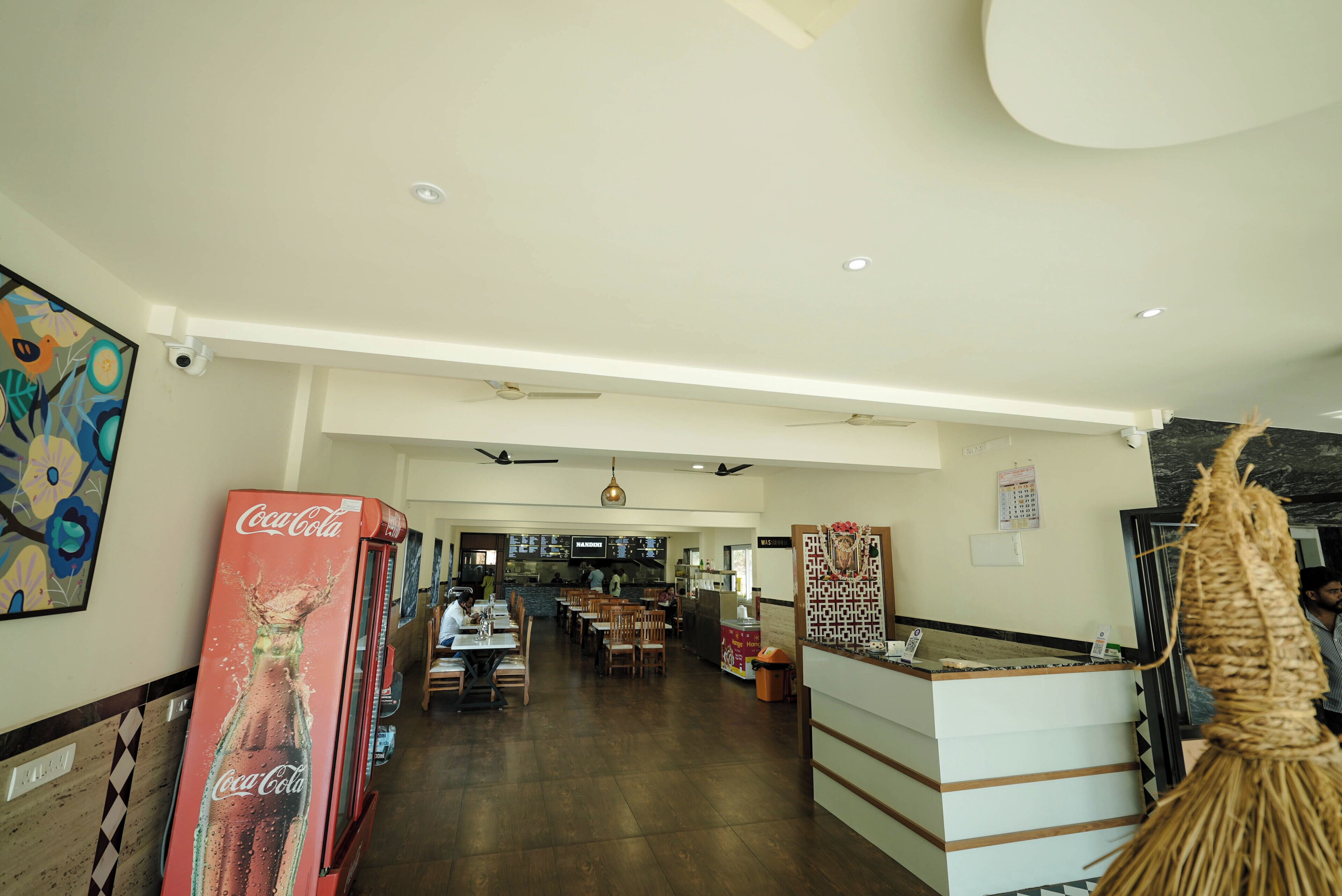 Un hall d’hôtel spacieux, équipé d’un distributeur automatique de Coca-Cola, d’un comptoir de réception et d’un espace détente avec des tables et des chaises.
