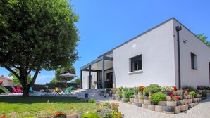 Ein modernes Gebäude mit überdachter Terrasse, Sitzgelegenheiten im Freien und einem Garten mit erhöhten Pflanzkästen.