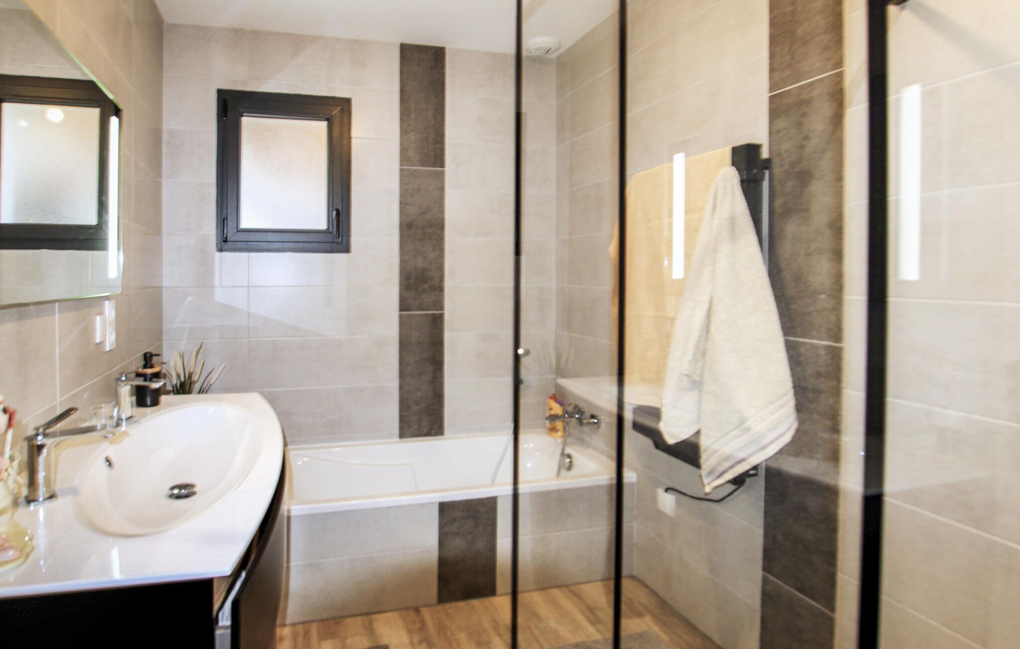 Une salle de bain moderne avec une douche à parois de verre, une baignoire et un lavabo surmonté d’un miroir.