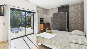 A modern bedroom with a large bed, a wardrobe, and a bathroom with a patterned wall. - VILLA PROVENÇALE AVEC PISCINE (Montauroux)