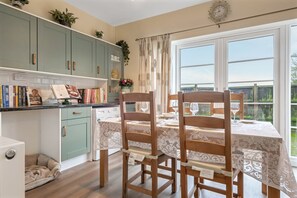 A kitchen with a dining area, a washing machine, and a view of the outdoors. - Pools Cottage 2-Head Cooks Cottage in Warwickshire (Kenilworth)