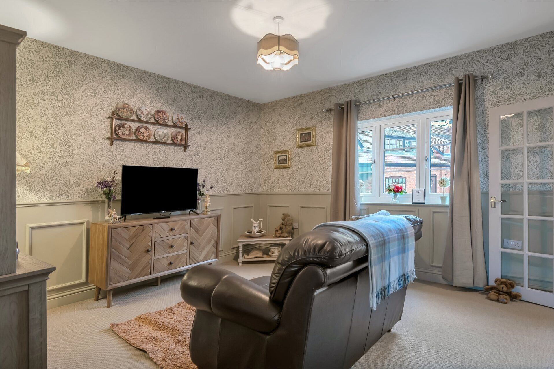 A living room with a sofa, television, decorative items, and a window with a view.