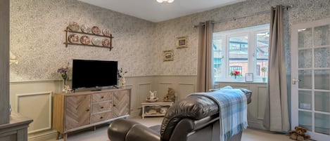 A living room with a sofa, television, decorative items, and a window with a view.