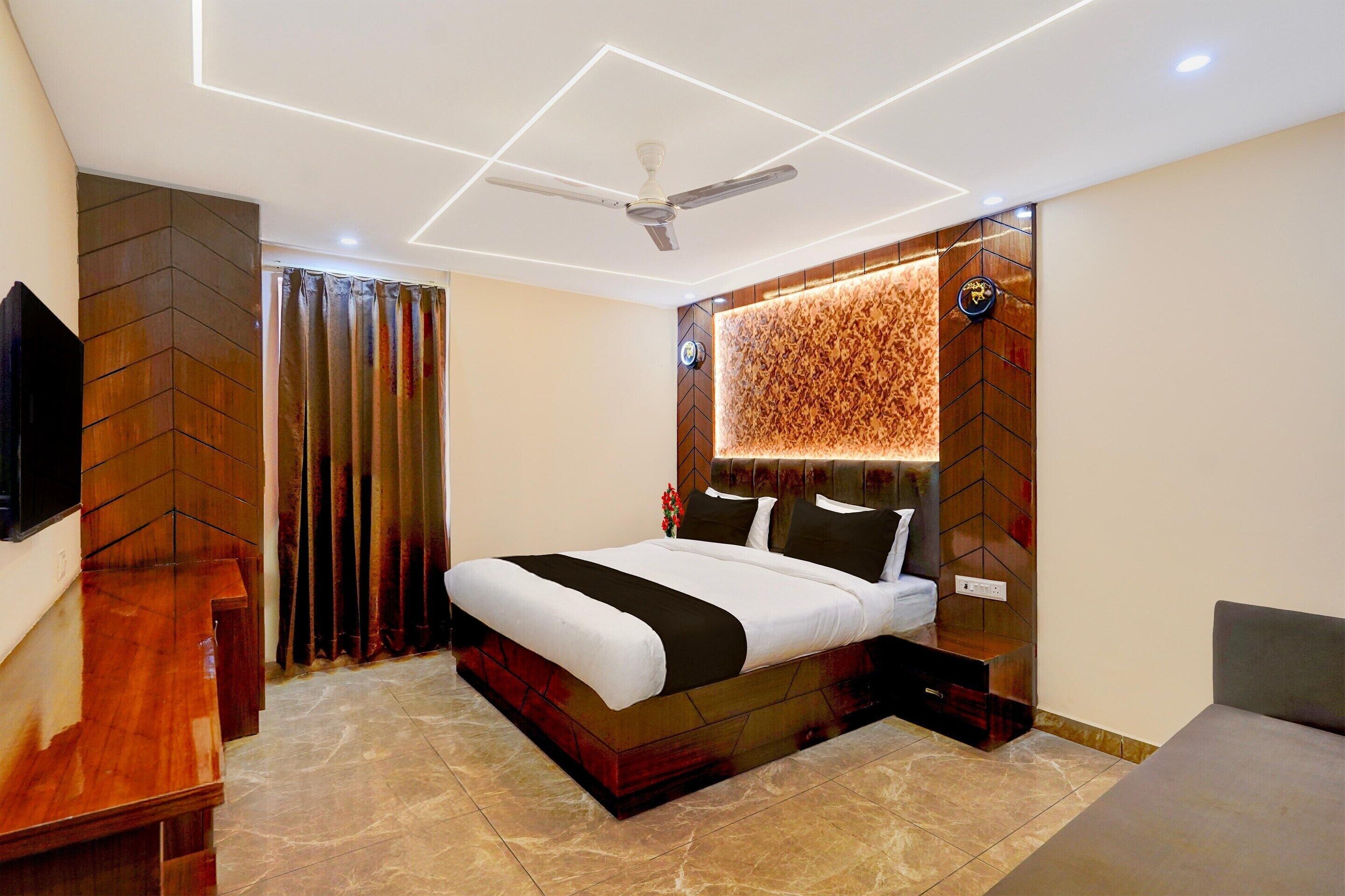 Een moderne slaapkamer met een groot bed, een plafondventilator en een televisie aan de linker muur.