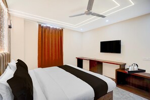 A hotel room with a bed, a desk, a television, and a ceiling fan. - Townhouse Dharampur Railway Station (Dehradun)