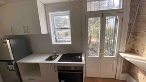 Eine kompakte Küche mit Fenster, Spüle und einem eingebauten Backofen.