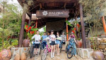 A wooden structure with a sign reading 'HALORA Puluwong Retreat' surrounded by potted plants and bicycles.