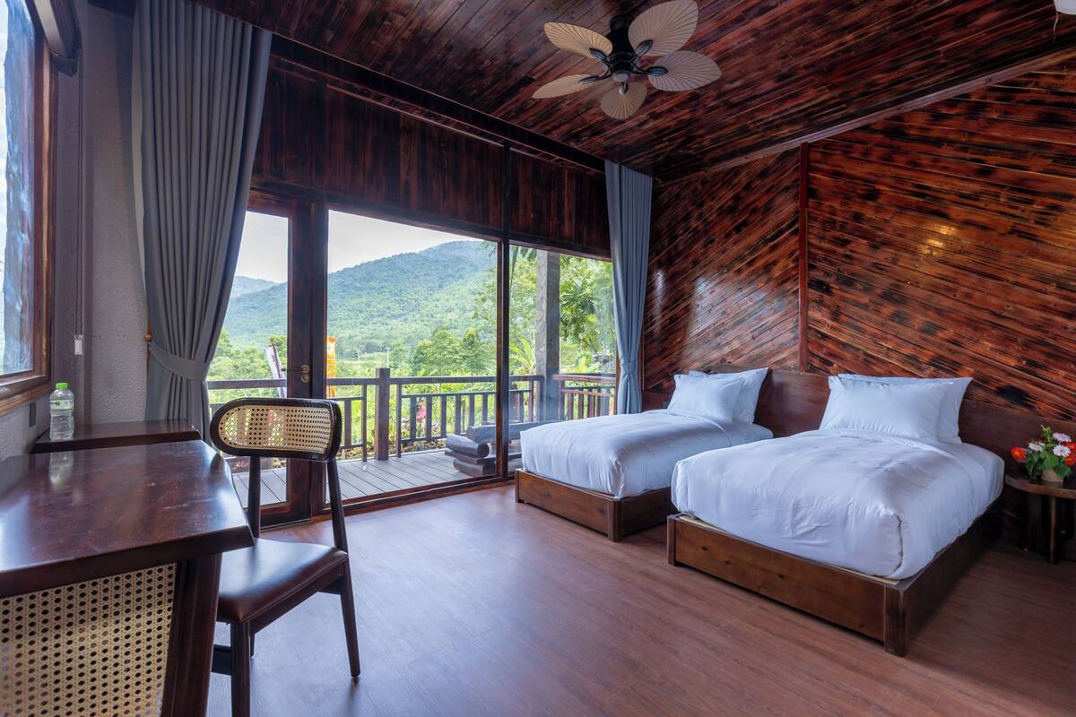 A wooden room with a bed, a desk, and a chair.