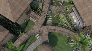 A courtyard with a central stone circle, surrounded by wooden walkways and various plants. - Halora Puluong Retreat (Pu Luong)