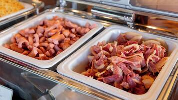 A buffet with various food items including ham and sausage.