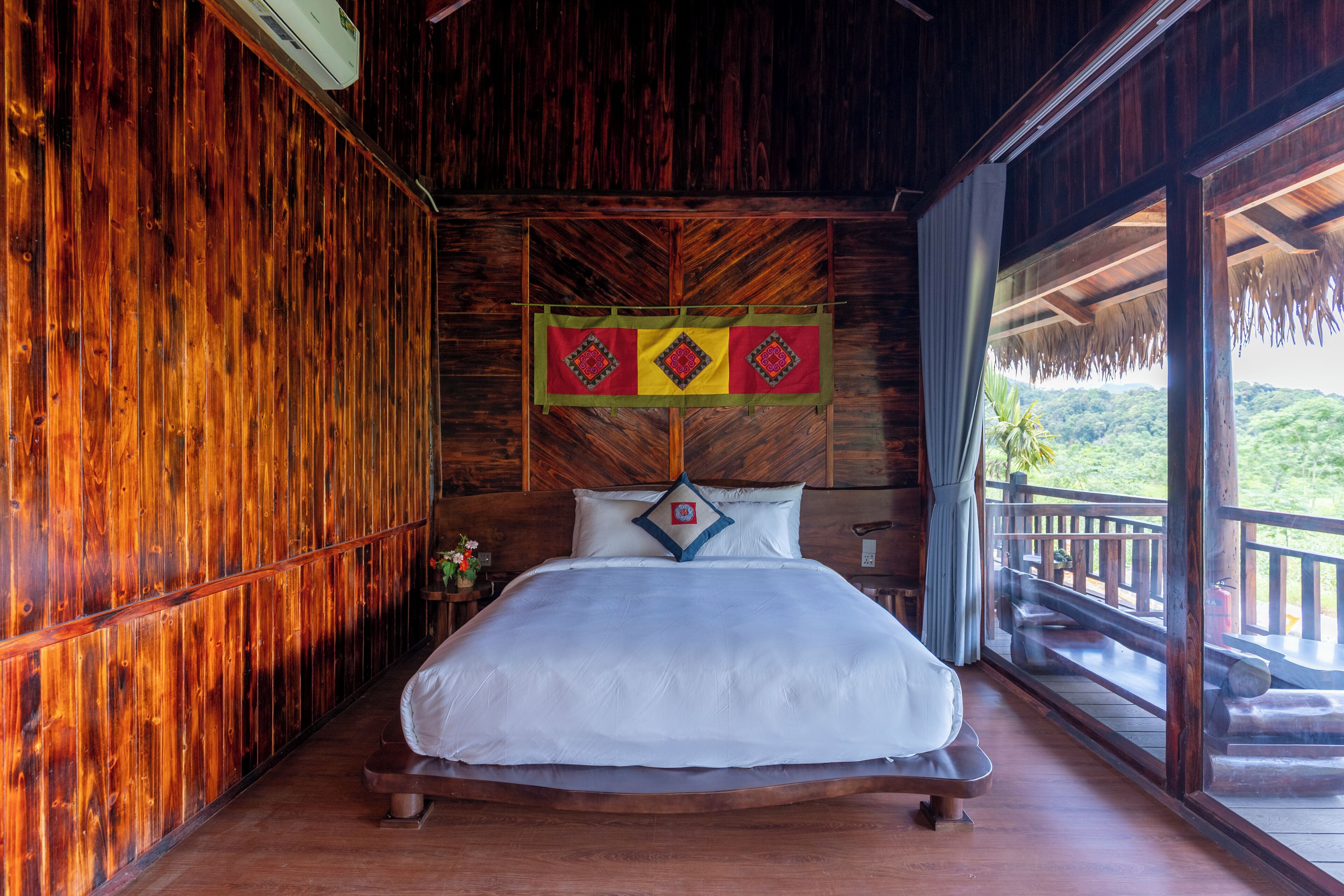 A wooden room with a bed, a window, and a view of greenery.