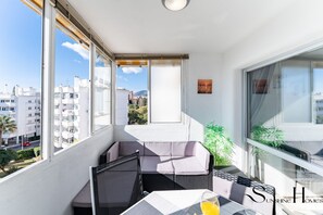 A balcony with a view of buildings, a table with a glass of orange juice, and a chair. - Seaview Retreat Apartment with Pool REF067 (Benalmádena)